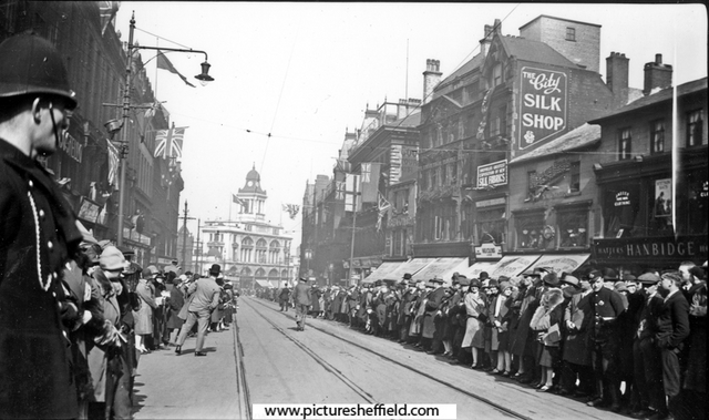 Unidentified royal visit passing Fargate, possibly Elizabeth, Queen Mother, 1934. Shops include No 41/43, J.B. Eaton Ltd., Drapers and Marsh Brothers (Electricians) Ltd., No 37, H.E. Closs and Co. Ltd., Silk Merchants
