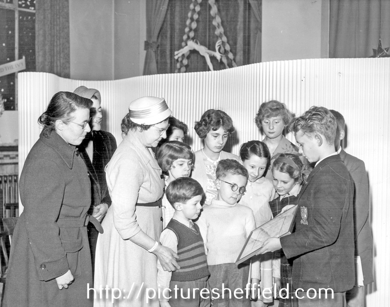 Mrs. Thorpe, wife of chairman of Libraries, Art Galleries and Museums Committee, Coun. Mrs. Jowett and Coun. Mrs. Goldring with John Pilley holding award for best decorated Childrens Library, Firth Park Branch Library, Christmas 1958