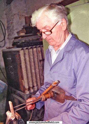 Stan Shaw (1927 - 2021) using a parser to cut shields (nameplates) in pocket-knife handles at his workshop, Garden Street