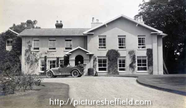 Distance shot of house as featured in arc02574 and arc02575 in front of which is a motorcar with two ladies inside