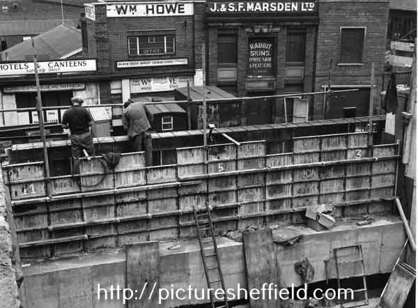 Construction work at junction of Shude Hill and Commercial Street showing offices behind of Wm. Howe, fish and poultry merchants and J. and S. F. Marshall, rabbit skin merchants