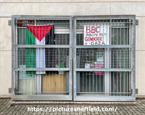 ‘BBC Tell The Truth - Genocide in Gaza’ placard alongside Palestinian flag (positioned opposite BBC Radio Sheffield between Shoreham Street and Brown Street)