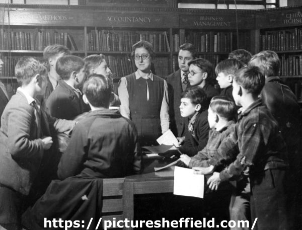 Miss Charlesworth with a group of boys in the Central Library during school instruction
