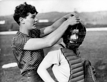 Member of the Sheffield Ladies Baseball Team assisting the 'Catcher' with her face guard