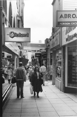 Shoppers in Chapel Walk showing No. 37 Charles Clinkard, shoe shop with the Crucible Theatre in the background
