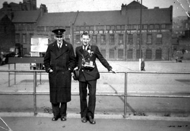 Bus conductor Dennis H Barley (right) and unnamed Regulator (left) at Pond Street Bus Station, Sheaf Island Works - Joseph Rodgers and Sons Ltd., cutlery manufacturers (No. 6 Works) in background
