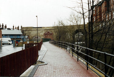 Completed section of the Five Weirs Walk footpath lookig towards the Victoria Station Viaduct with the Royal Victoria Holiday Inn right