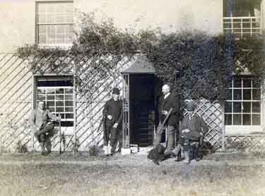 Shooting party of four individuals (including Arthur Wightman, standing to the right of the door with a gun under his arm and dog at his feet) outside a building thought to be Edgefield House, Bradfield, 1880s