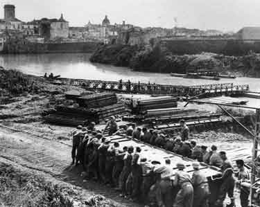 Troops of the 46th West Riding and North Midland Divisional Engineers constructing the first operational Bailey Bridge over the River Voltumo, Italy