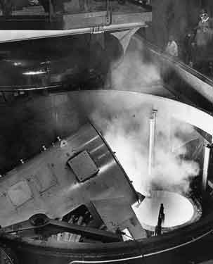 High frequency melting furnace, here seen discharging molten metal into the ladle during melting trials, is normally totally enclosed within the vacuum tank