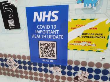 Covid-19 pandemic: anti-Covid restrictions sticker - NHS Covid 19 Important Health Update.  Scan me. 