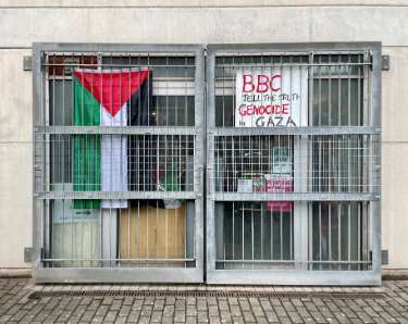 &lsquo;BBC Tell The Truth - Genocide in Gaza&rsquo; placard alongside Palestinian flag (positioned opposite BBC Radio Sheffield between Shoreham Street and Brown Street)