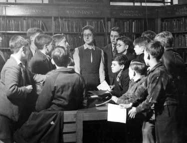 Miss Charlesworth with a group of boys in the Central Library during school instruction