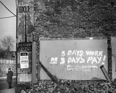 Graffiti on demolished building saying '5 days work for 5 days pay'