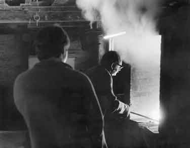 Brian Lidster, metalsmith, putting crucible into the furnace [Brass Foundry, Carver Lane]