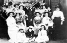 Wedding photograph of Mr. and Mrs. Wilkinson, bridegrooms parents (man with hat and woman with bouquet) centre behind the couple