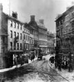 View: s17279 High Street from Market Place, before the street widening of 1896, premises include No 64A, High Street, India Rubber, Gutta-Percha, No 52-56 John Walsh, draper, Clarence Hotel in background (tallest building), No 55, Market Place, J. Evans, confecti