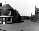 No. 18 corner shop, Baldwin Street and Nos. 1, 3, 5, etc. (left), Nos. 10 - 16 (right), St. Charles Street with the roof of No. 2 St. Charles Roman Catholic Church