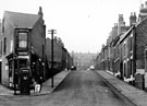 View: s21030 Nos. 58 corner shop, 40, 38 etc. (left) and 67, 65 etc. (right), Jamaica Street, Burngreave from junction with Kingston Street/ Petre Street looking towards Sedan Street and Grimesthorpe Road in the background