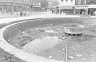 View: s24465 The empty Goodwin Fountain, Fargate looking towards Leopold Street  showing Wilson Peck, music centre; H.L Brown and Son Ltd, jewellers and  Cantors Ltd., house furnishers
