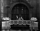 Queen Elizabeth II and HRH Duke of Edinburgh waving to the crowds from the balcony of the Town Hall, Pinstone Street with Lord Mayor, J.H. Bingham in the background