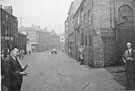 View: t04874 Mr. C.W. Claxton of Sheffield Twist Drill and Steel Co., (watched by Mr. F. Green) conducting a drop test on one of the first butt-welded drills, junction of Napier Street and Solferino Street, building on the right used as a hammer factory