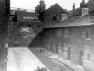 Looking towards the wall belonging to F.J. Brindley and Sons, Central Hammer Works, from Mate's Square, off River Lane, showing slum back to back housing