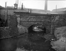Meadowhall Road Bridge over Blackburn Brook at the City Boundary looking up stream with Meadow Hall Works in the background