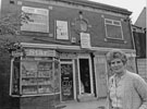 Pat Waller outside her newsagents shop, Mac's News Nos. 100 and 100d Cut Above, gents hairdressing, Wulfric Road, Manor