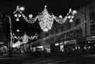 Christmas decorations on The Moor showing (r. to l.) No. 123 Curtess Shoes Ltd., No. 121 J. and F. Stone, radio supplies dealers, Nos. 117 - 119 Maypole Dairy Co. Ltd., grocers and No.115 Readicut Wools Ltd., wool dealers