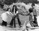Children playing with a fountain, probably in a park.
