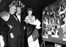 Actor Dinah Sheridan looking at photographs of the opening of the Odeon Cinema with her husband Sir John Davis (Chairman of the Rank Organisation) standing next to her