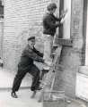 Workmen boarding up a window, Royal Hospital, West Street