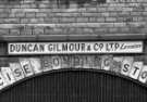 Wall sign above railway archway for Duncan Gilmour and Co. Ltd., lessees, mid 1970s