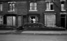 Woman cleaning her windows in unidentified derelict street, c.1970s Woman cleaning her windows in unidentified derelict street, c.1970s